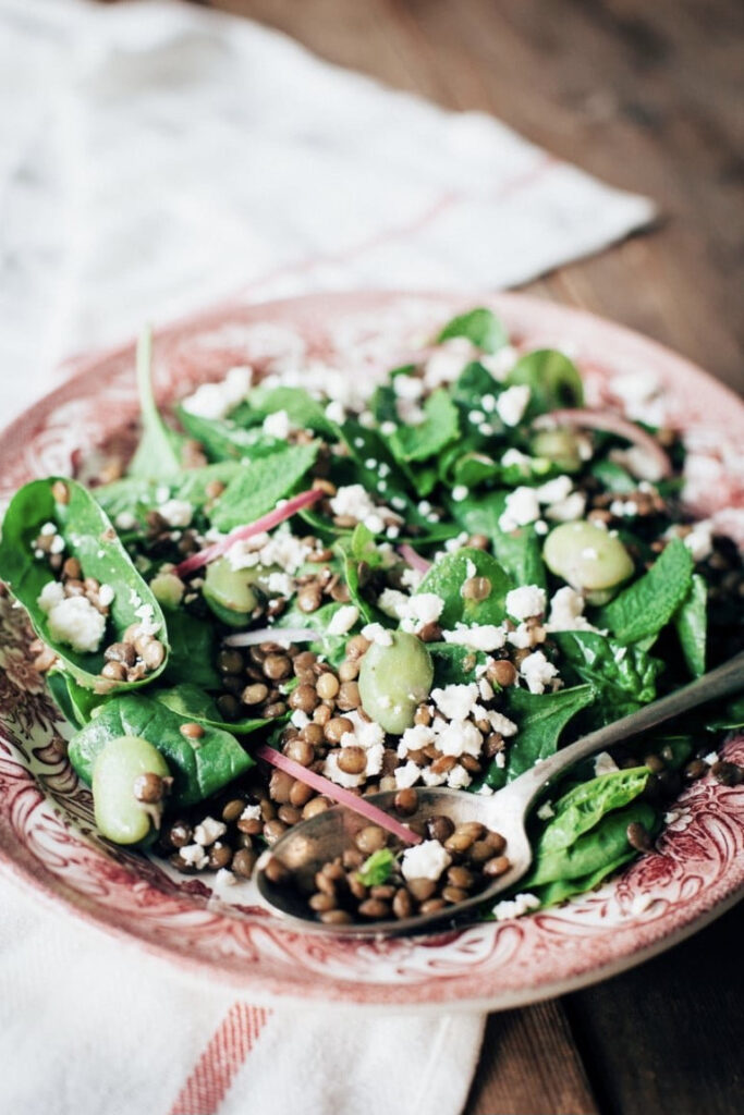 Angled view of lentil salad with broad beans and feta on a platter