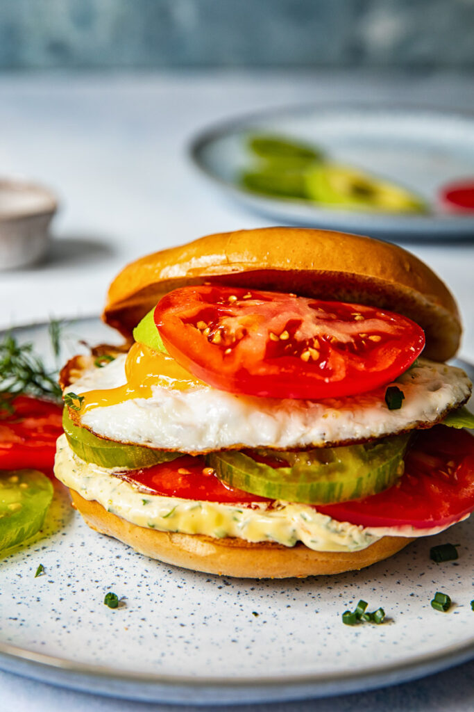 Bagel sandwich with the top angled off and a tomato on top