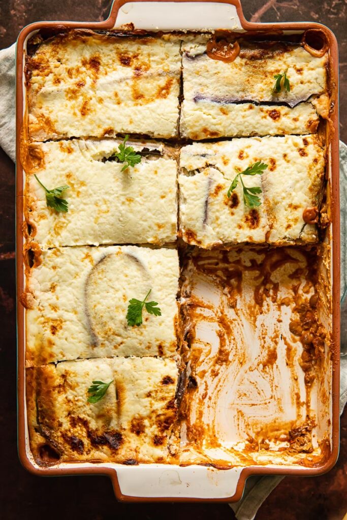 Veggie lentil moussaka in a baking dish with pieces removed