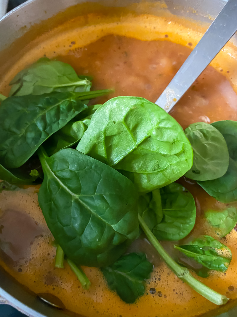 Spinach leaves added to soup pot