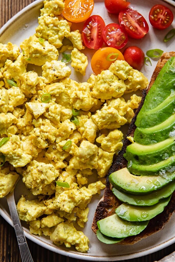 Plate of egg tofu scramble with avocado and tomatoes