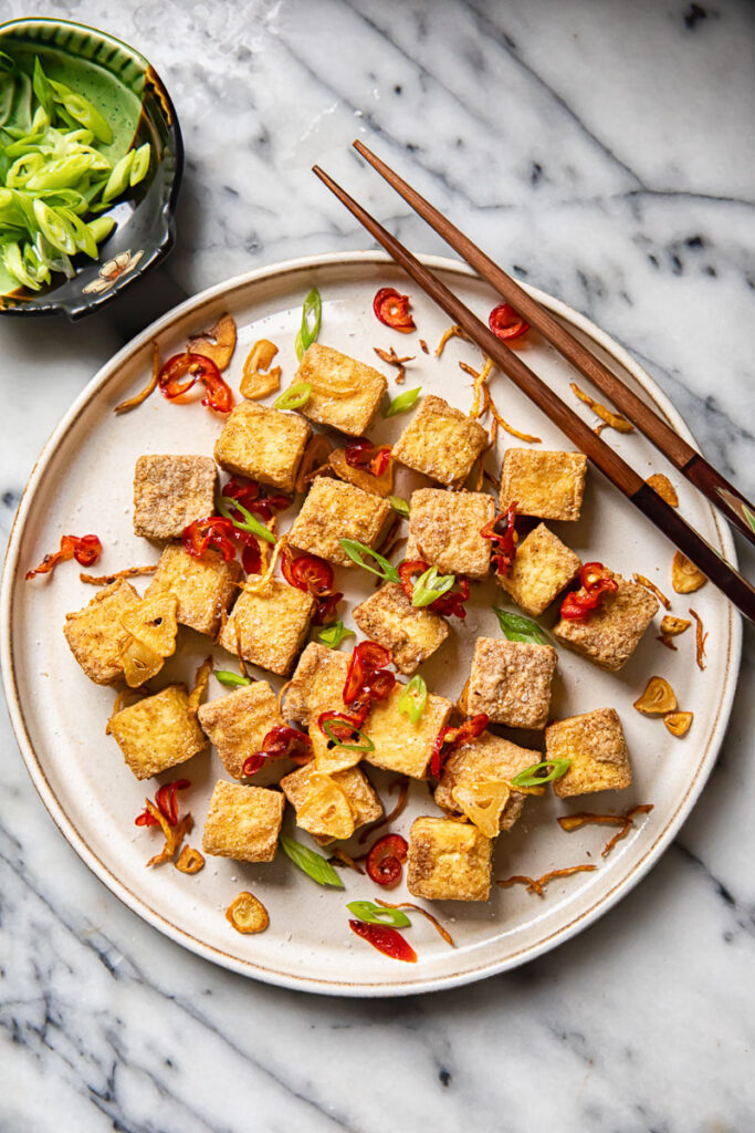 Plate of air fryer tofu bites with cop sticks and side dish of green onions