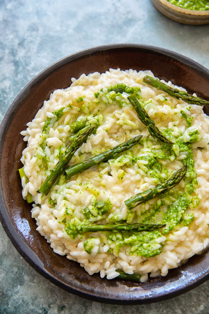 Plate with risotto topped with asparagus and pesto