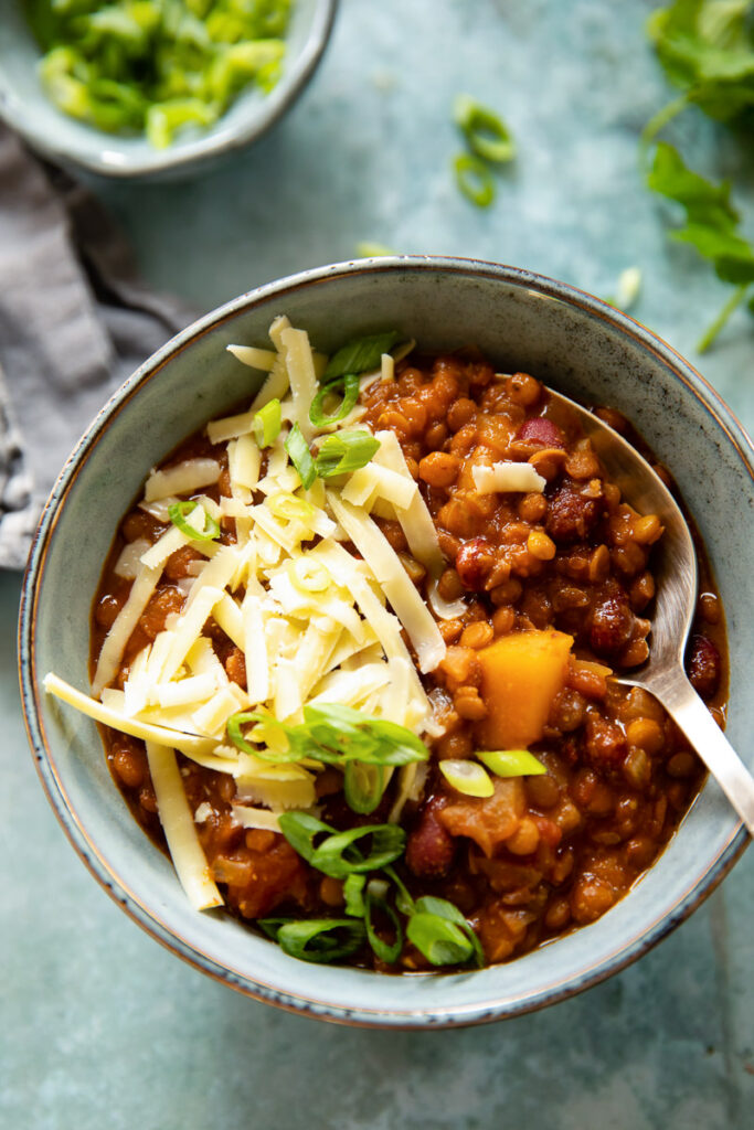 Bowl of vegetarian chili with grated cheese and spoon