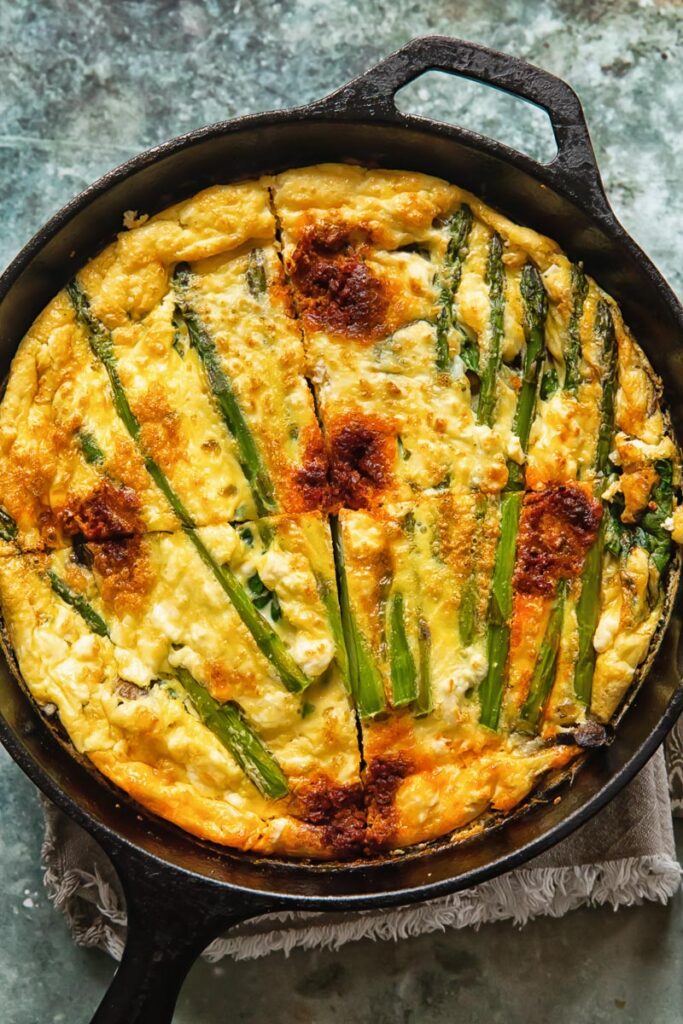 Vegetable frittata in a cast iron pan cut into quarters